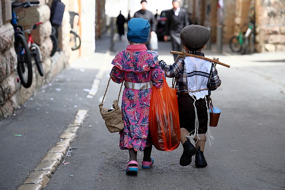Two children in Purim costumes walking in Jerusalem's Mea Shearim neighborhood